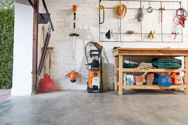 STIHL chainsaw and lawn mower being cleaned and prepared for winter storage in a dry shed